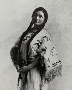 Native American woman with braided hair wearing traditional clothing