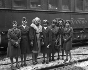 Photo of several Black women in military uniform in front of a train car.