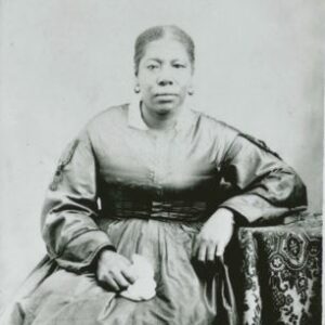 Black woman seated for a photo wearing a black silk dress