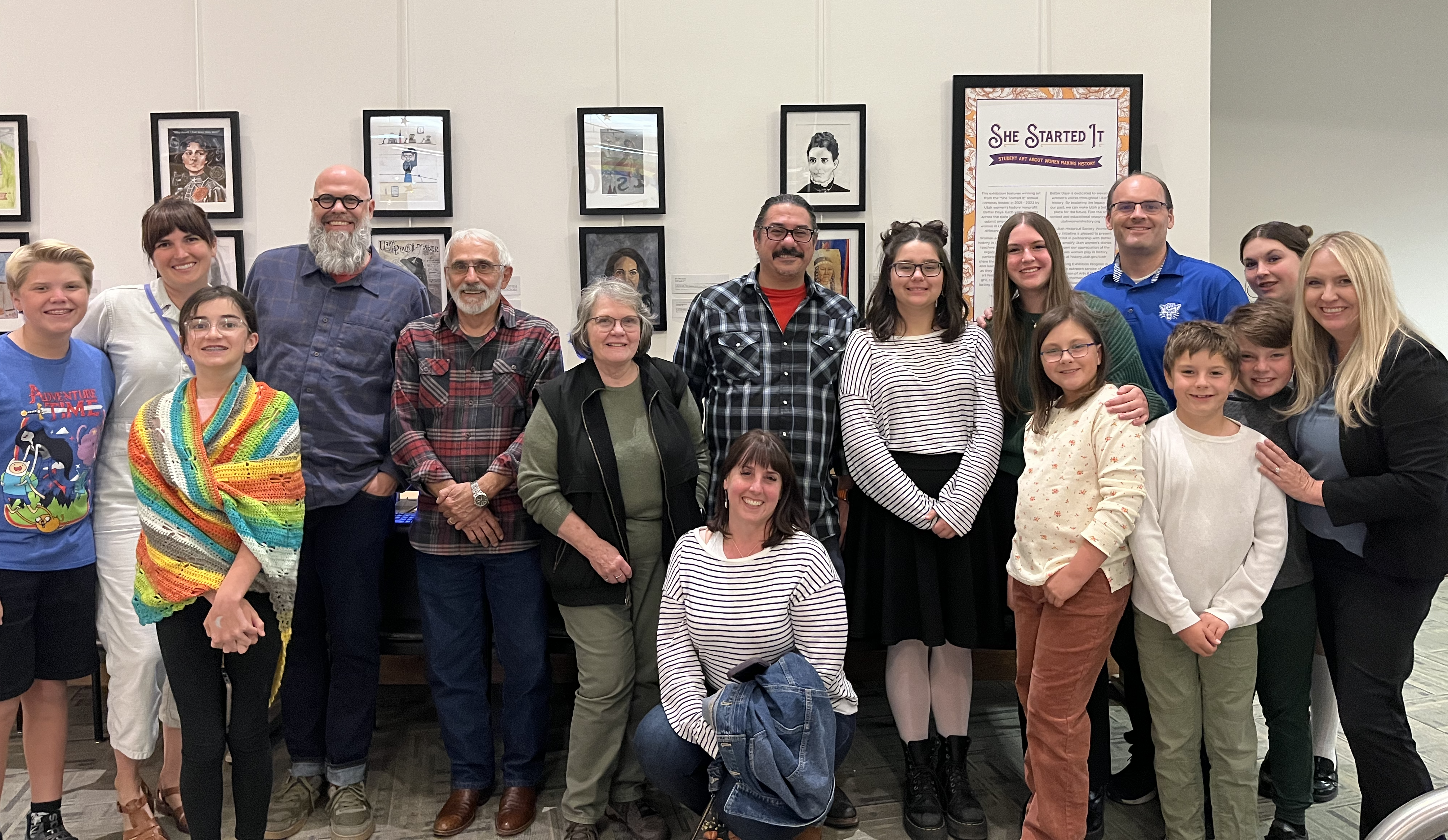 A group of students and their families in front of their art on display.