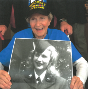 Older woman holding a photo of herself in Navy uniform during WWII.