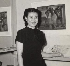 Woman standing next to a display of her art.