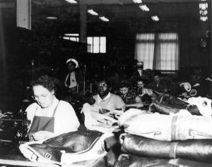 Photo of white and black women working at sewing machines.