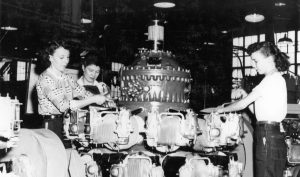 Women working on a large piece of machinery.
